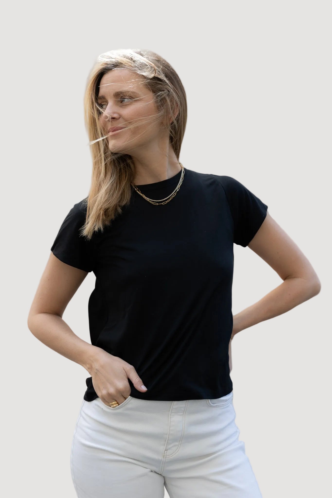 A woman wearing a black T-shirt and white pants, posing with one hand on her hip.