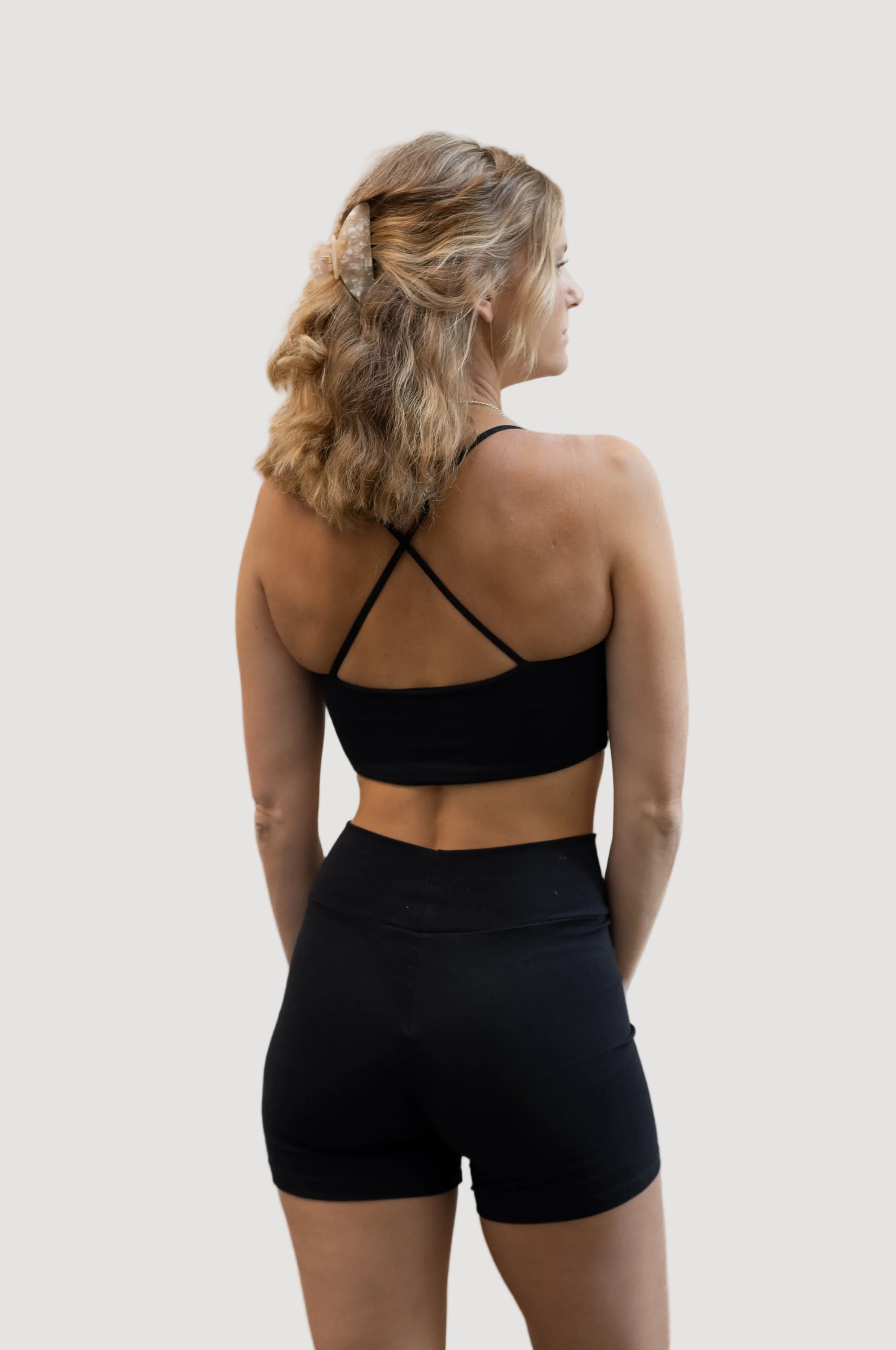 A person wearing black biker shorts and a matching sports bra, viewed from the back.
