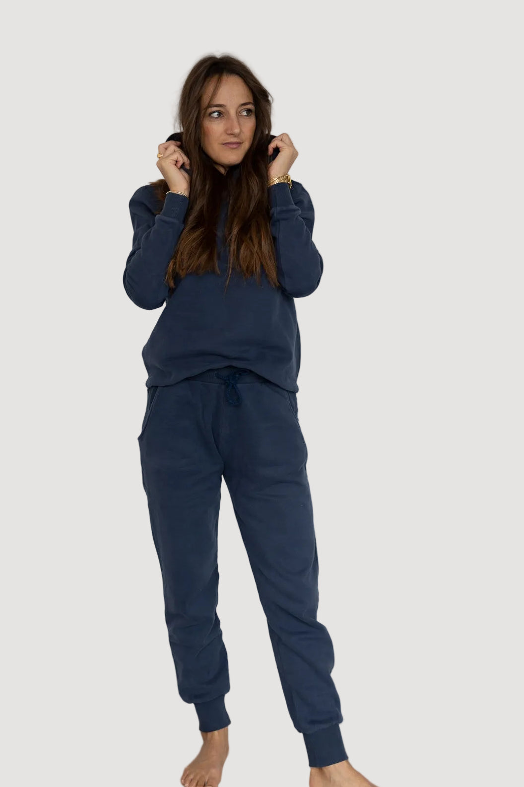 A person wearing a navy-colored hoodie and matching pants, standing against a plain background.