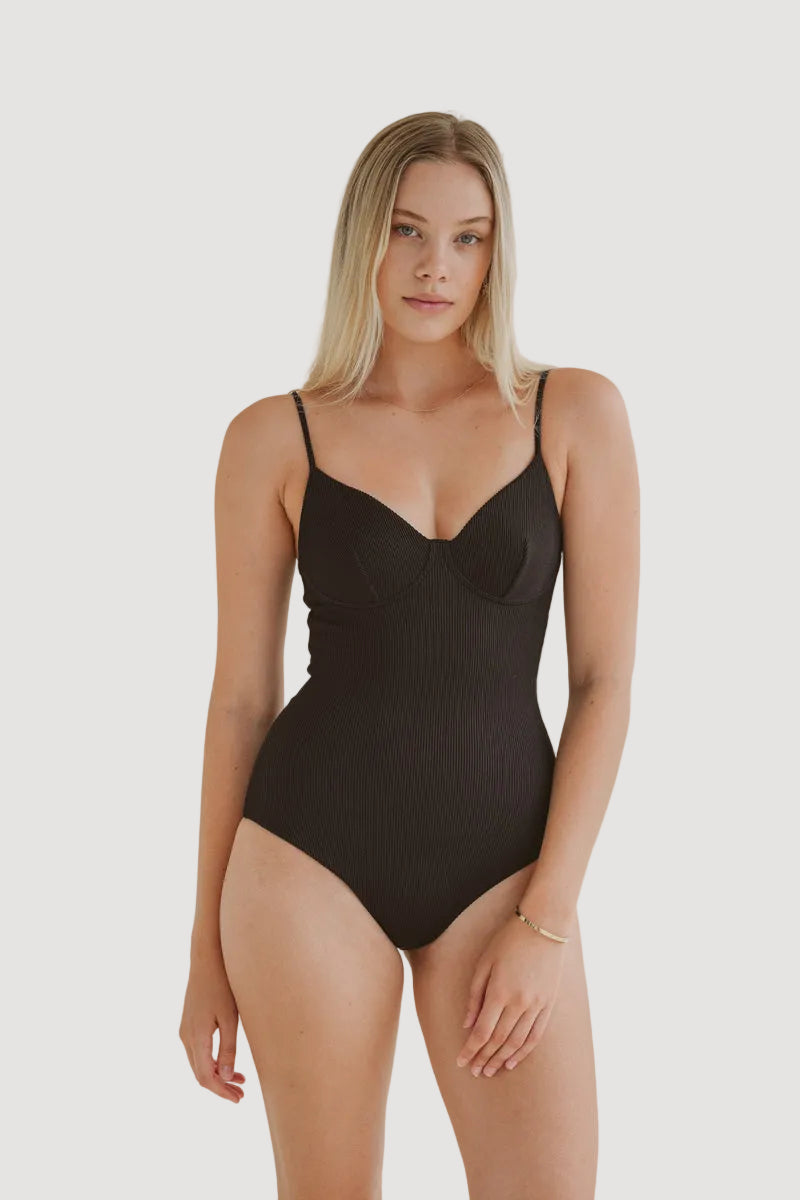A model wearing a black one-piece swimsuit with adjustable spaghetti straps and a V-neckline.