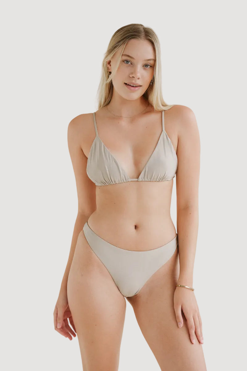 A female model wearing a beige shiny bikini top with adjustable straps and a matching bottom, standing against a neutral background.