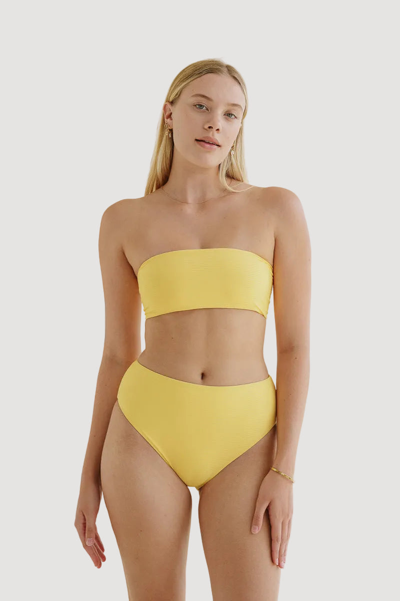 A woman wearing a yellow bandeau bikini top and matching bottoms.