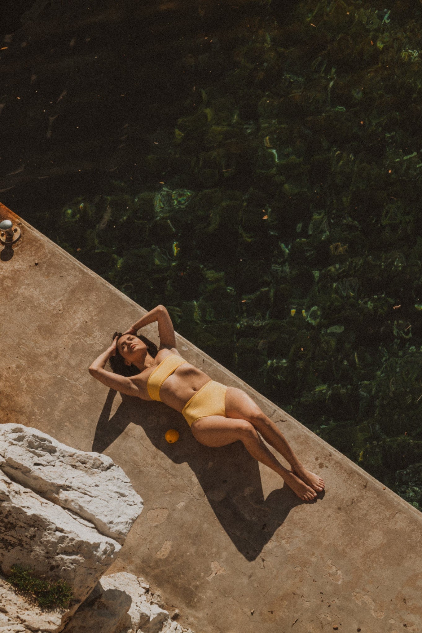 Person lying on a ledge by a body of water at night