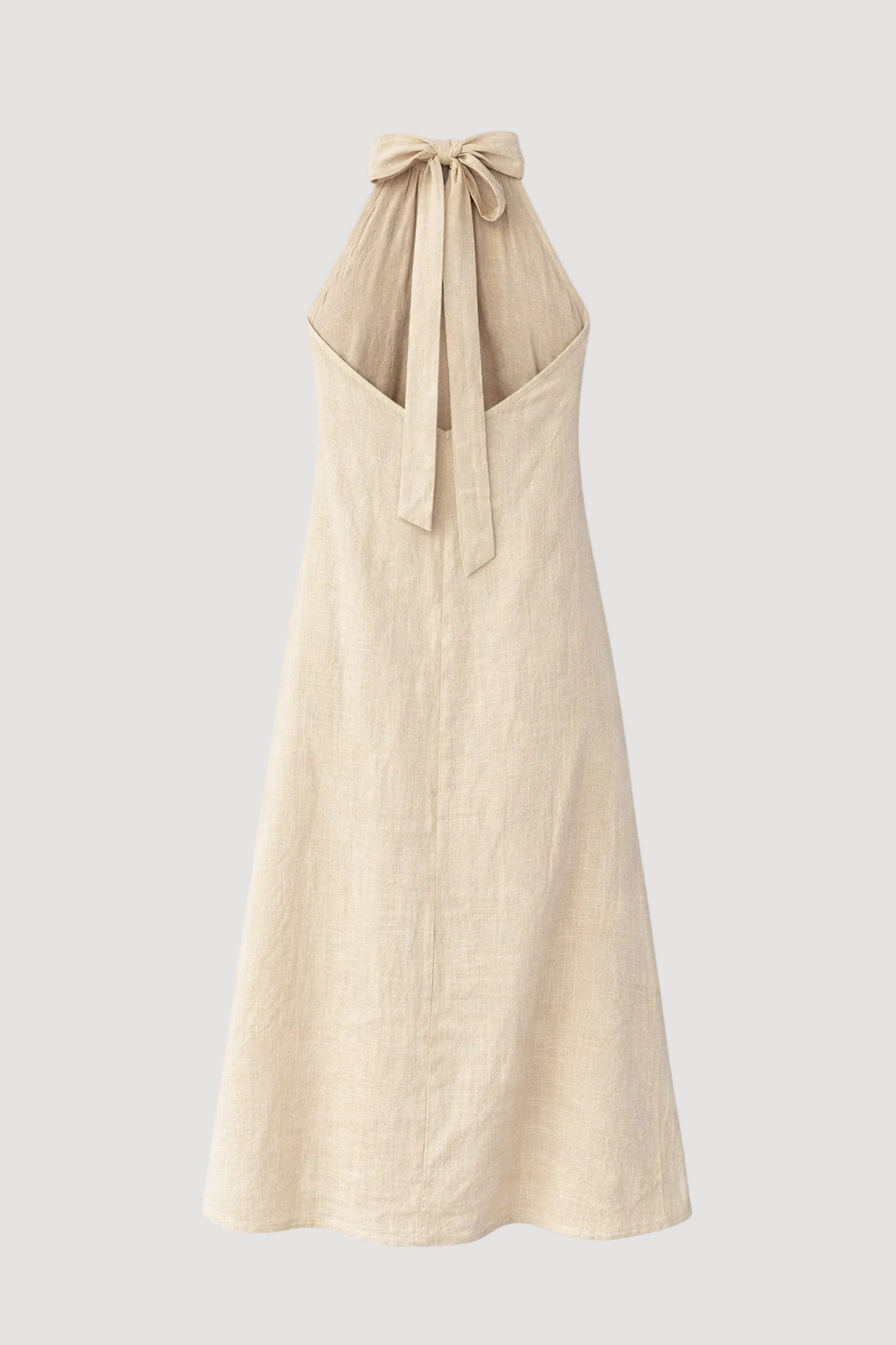 Beige halter neck dress with a bow detail on a white background