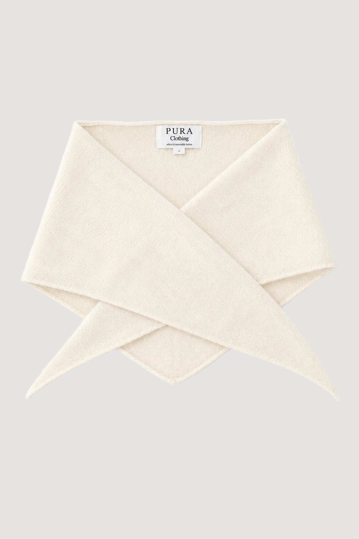 A cream-colored knit scarf folded and crossed, with a white brand label reading 'PURA CLOTHING' visible at the top center, set against a plain white background.