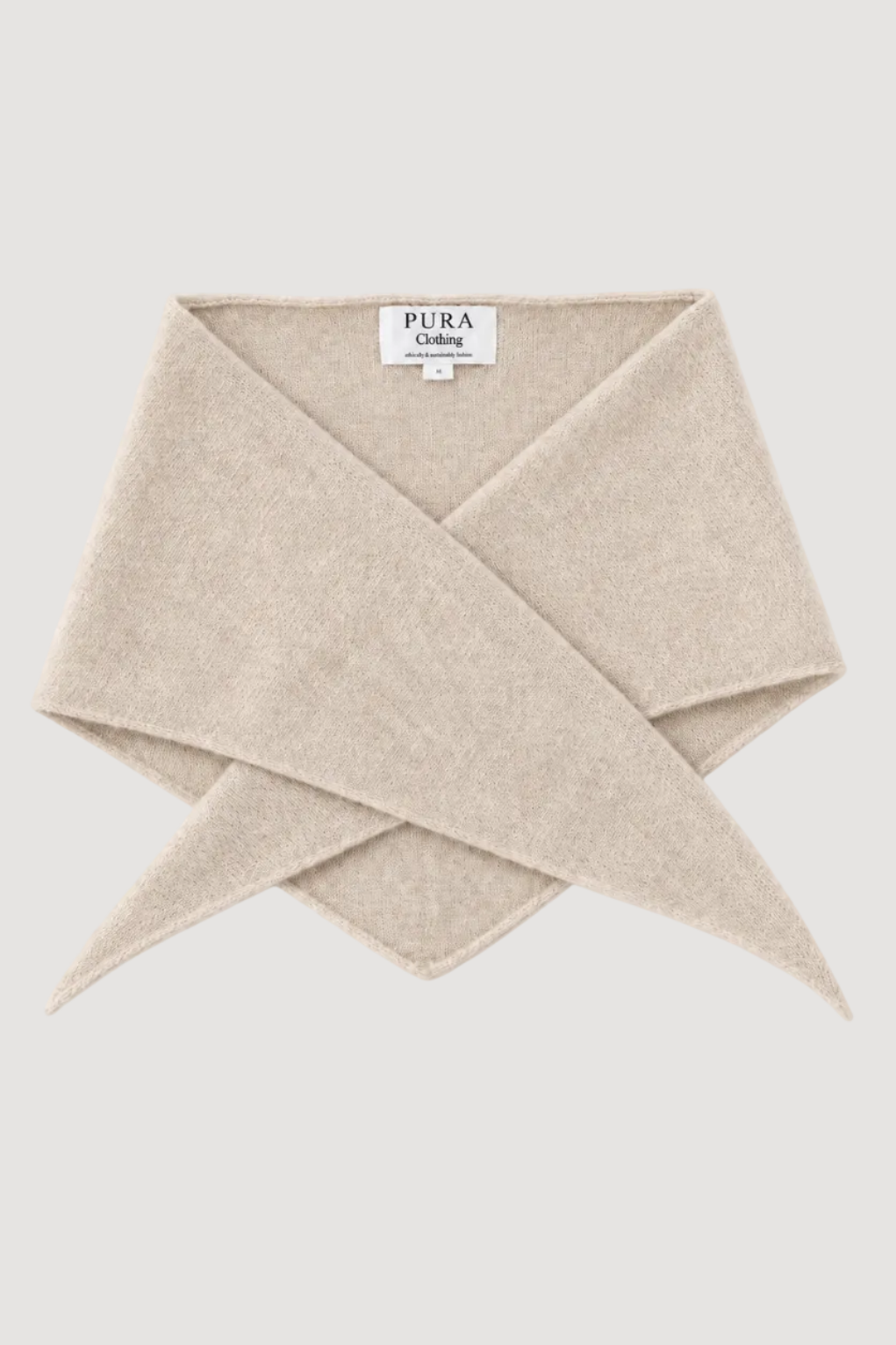 A folded beige knit scarf with a white brand label reading 'PURA Living' on a light gray background.