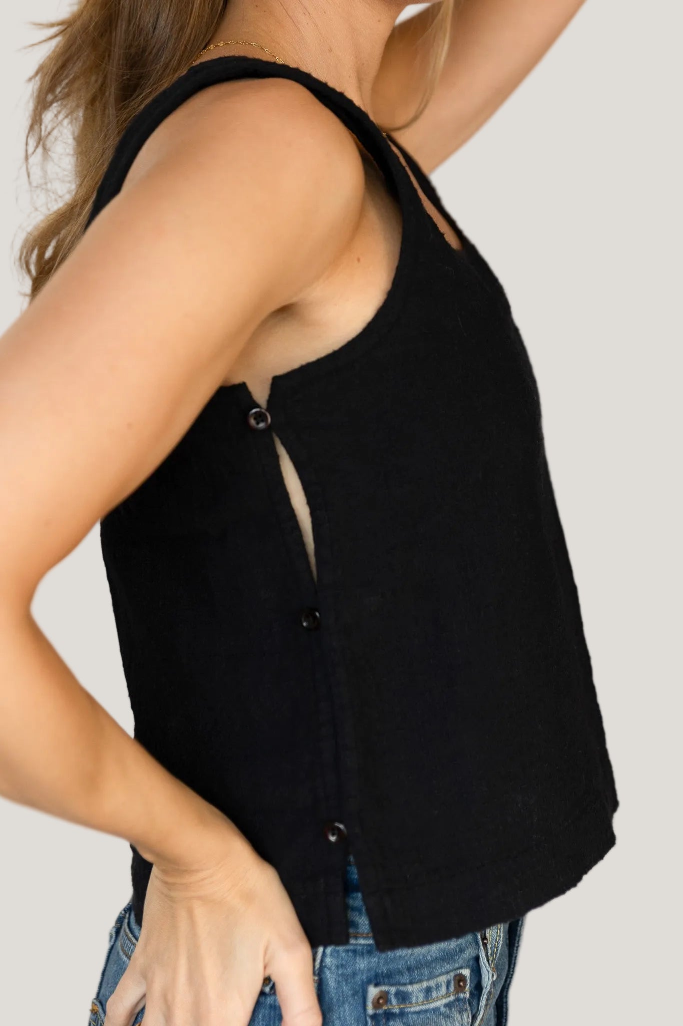 Black sleeveless top worn by a person on a plain background