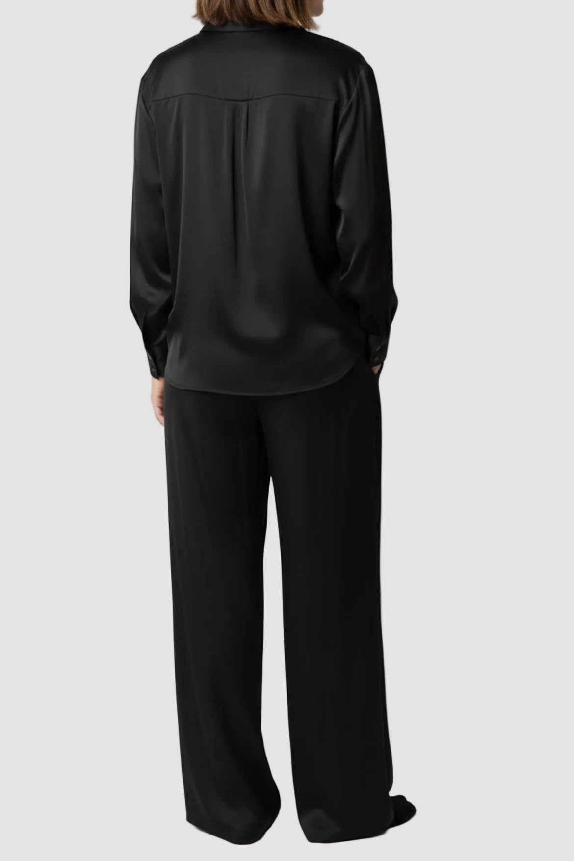 Person wearing a black satin shirt and pants on a white background