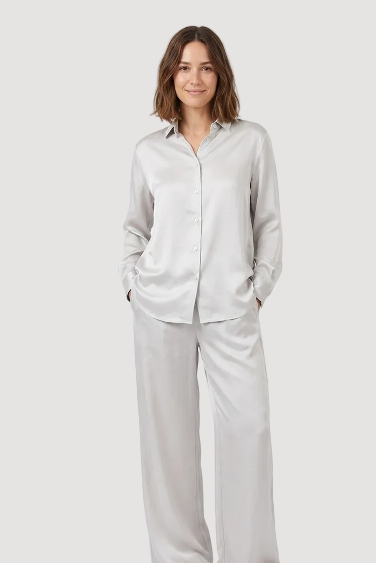 Woman wearing a light gray shirt and pants on a white background
