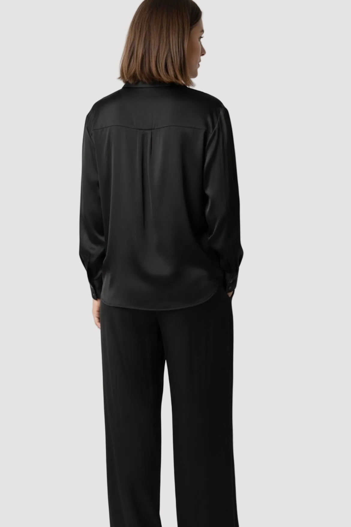 Person wearing a black satin shirt and pants on a white background