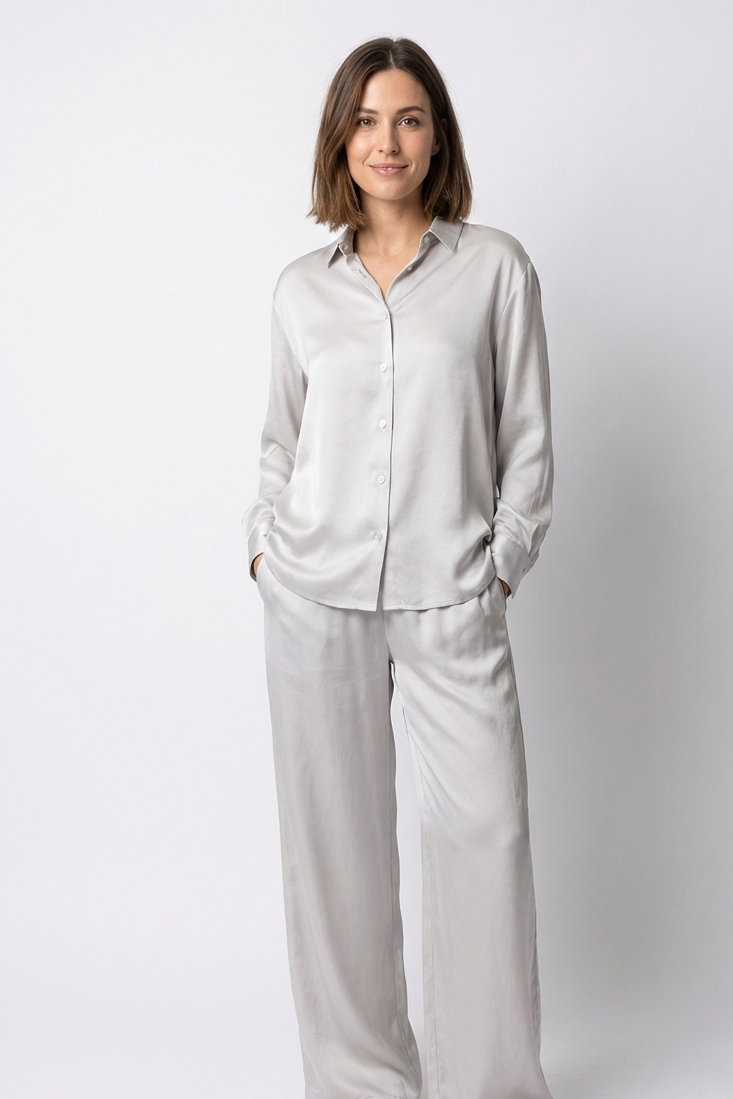 Woman wearing a light gray pajama set against a white background