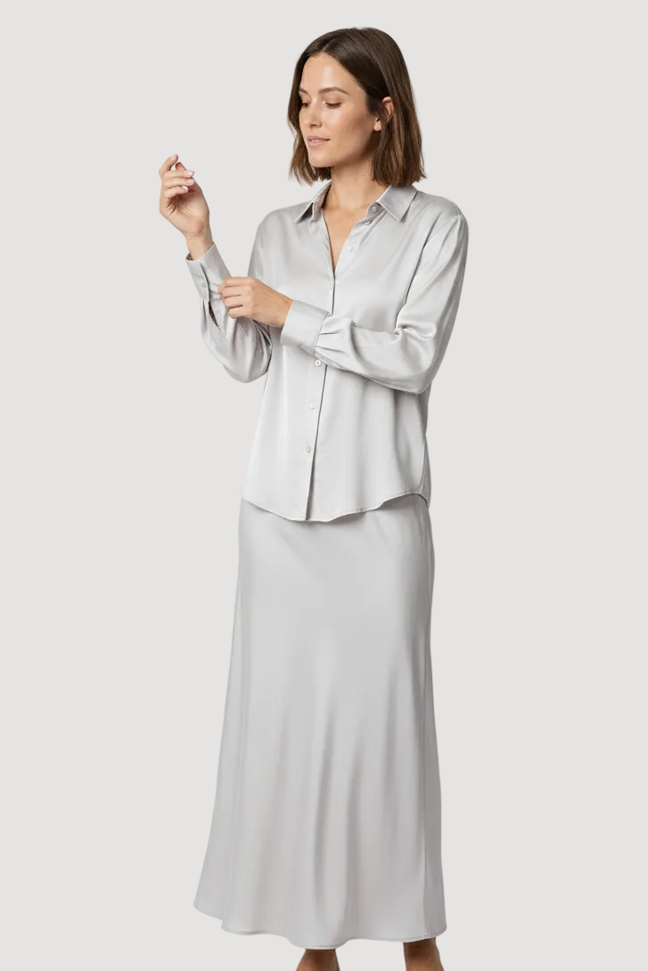 Woman wearing a light gray blouse and skirt set on a white background
