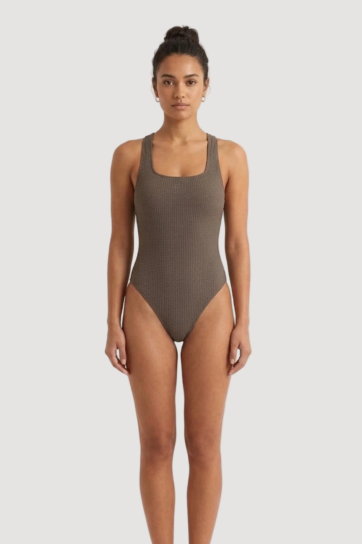 Woman wearing a brown swimsuit on a white background
