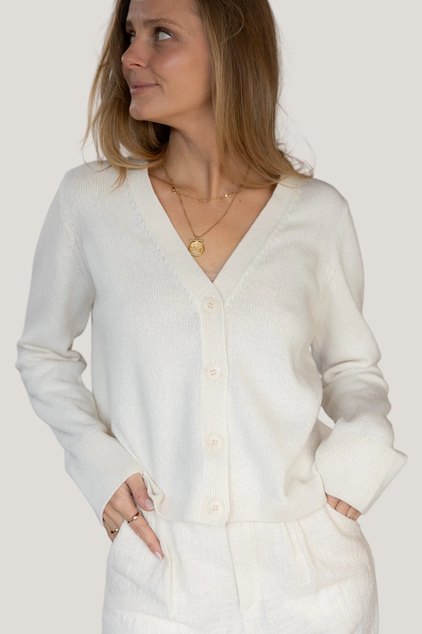 Woman wearing a white cardigan against a plain background
