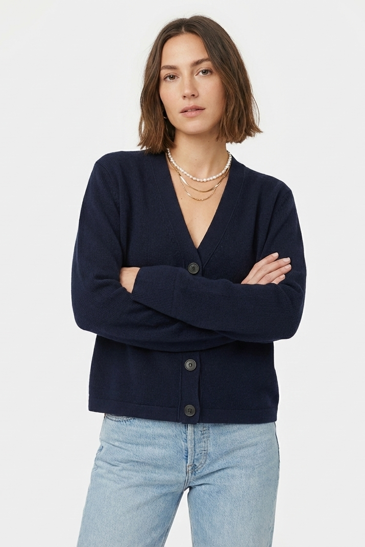 Woman wearing a navy cardigan and light blue jeans on a white background