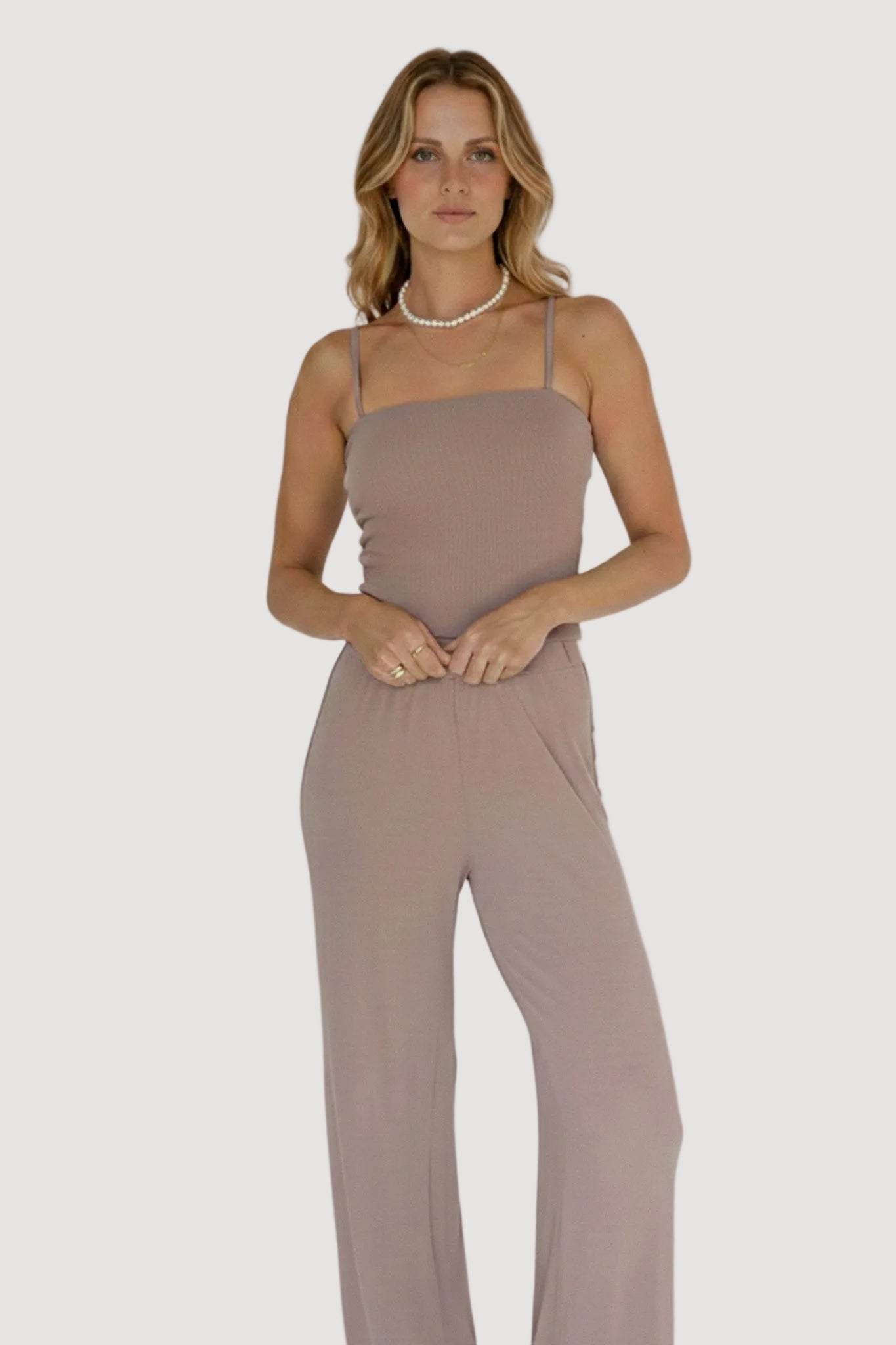 Woman wearing a brown jumpsuit against a white background