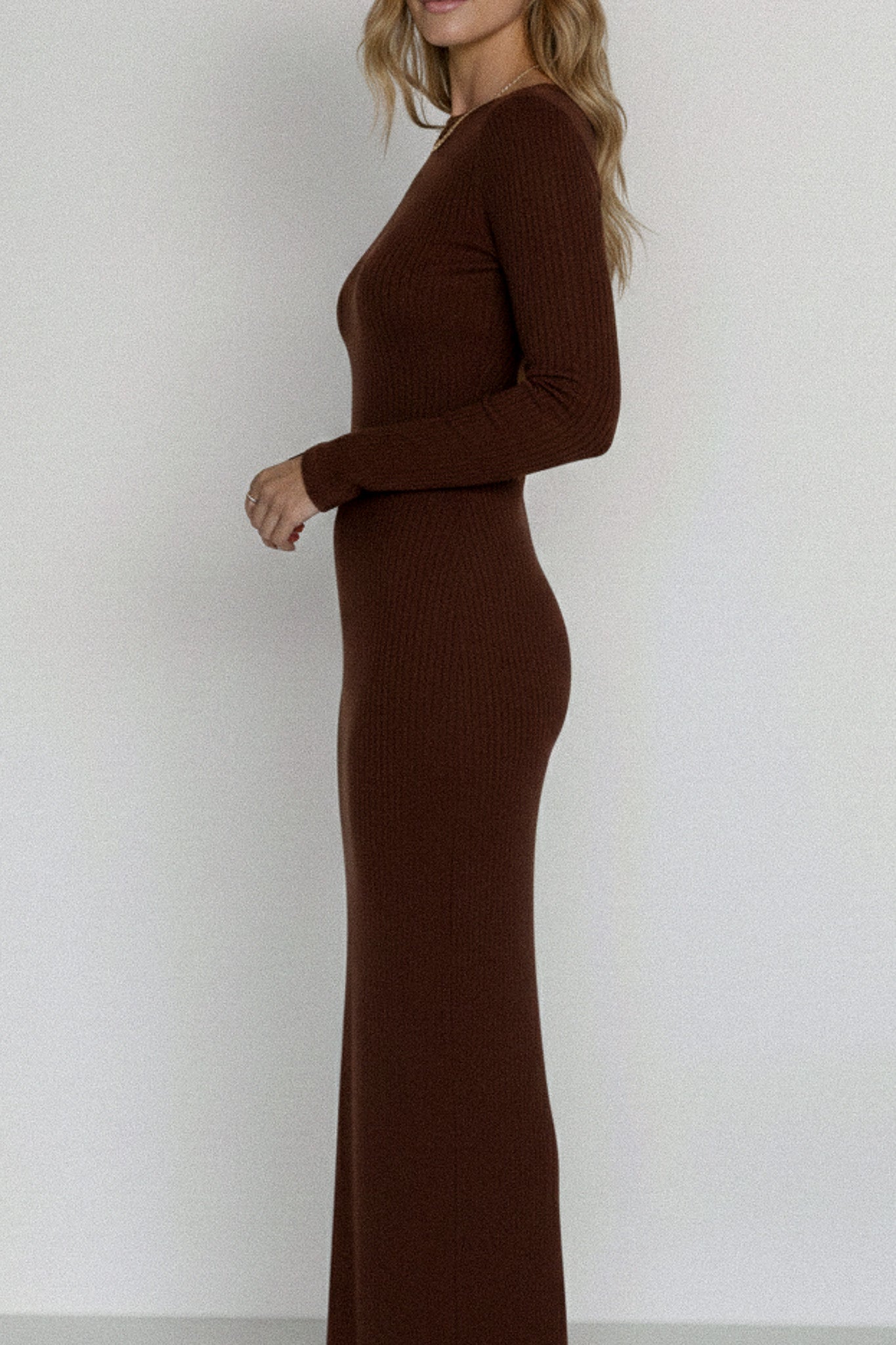 Woman wearing a brown ribbed dress against a white background