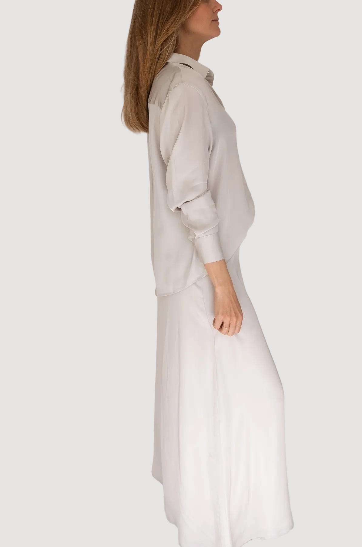 Woman wearing a long white dress against a plain background