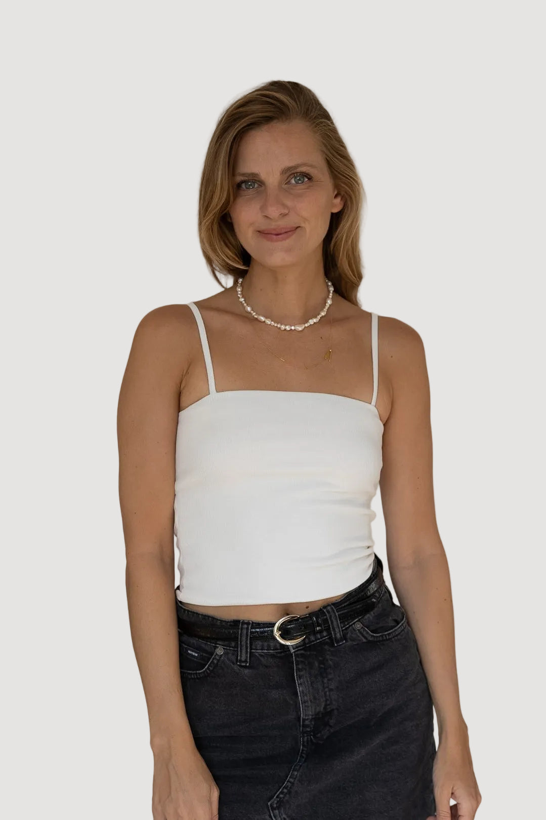 Woman wearing a white top and black skirt against a plain background