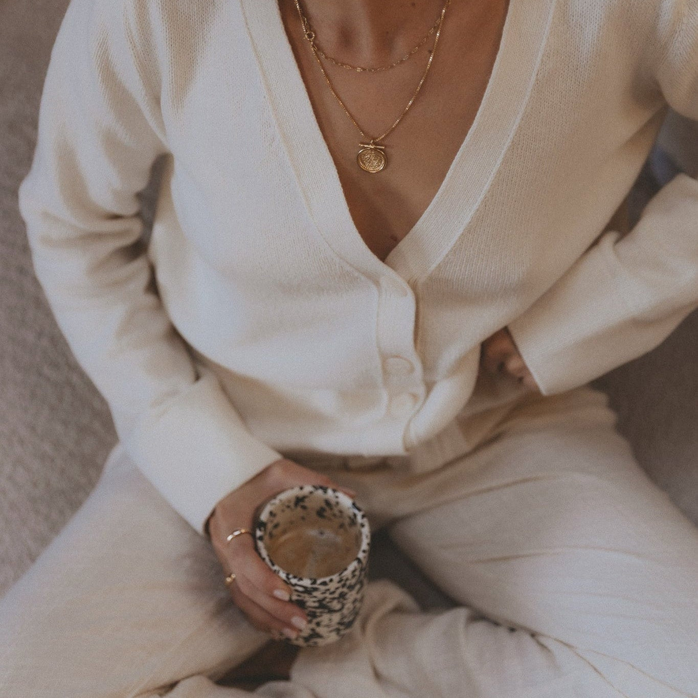 Person wearing a white outfit holding a decorative object on a neutral background