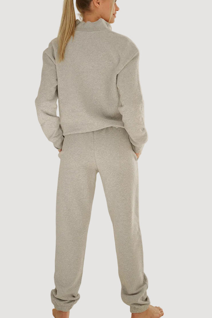 A woman shown from the back wearing a light gray heathered two-piece loungewear set consisting of a cropped long-sleeve top and matching sweatpants, against a solid light gray background.