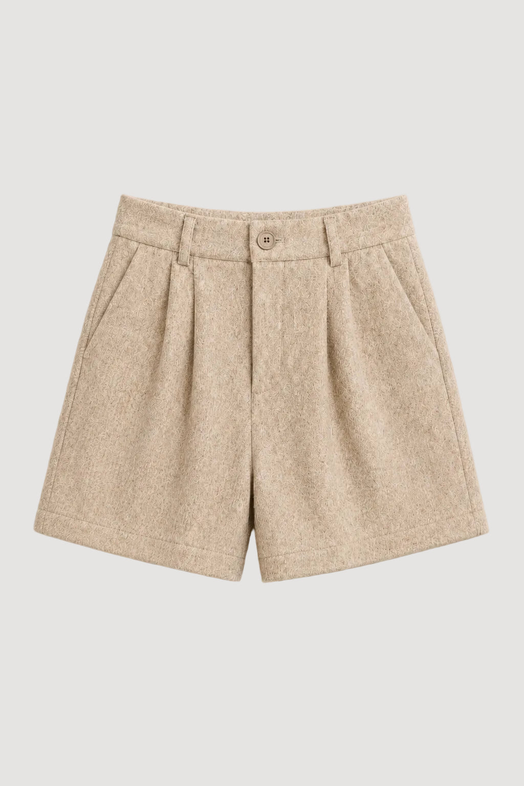 A pair of beige pleated shorts with a textured wool-like fabric, featuring a button closure and side pockets, laid flat against a light cream background.