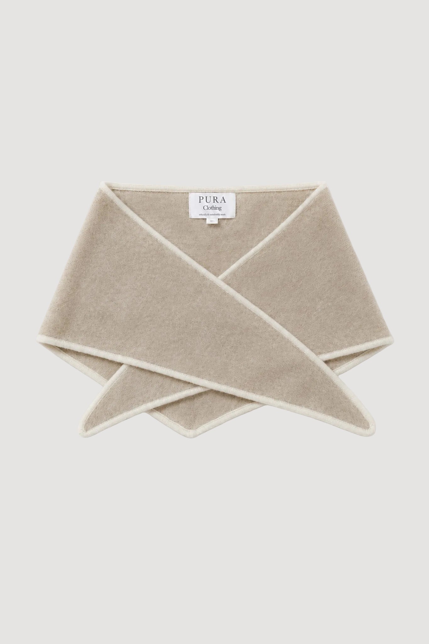 A folded beige knit wrap or scarf with a white border, displayed on a clean white background. A small white brand label reading 'PURA LALIQUE' is visible at the center.