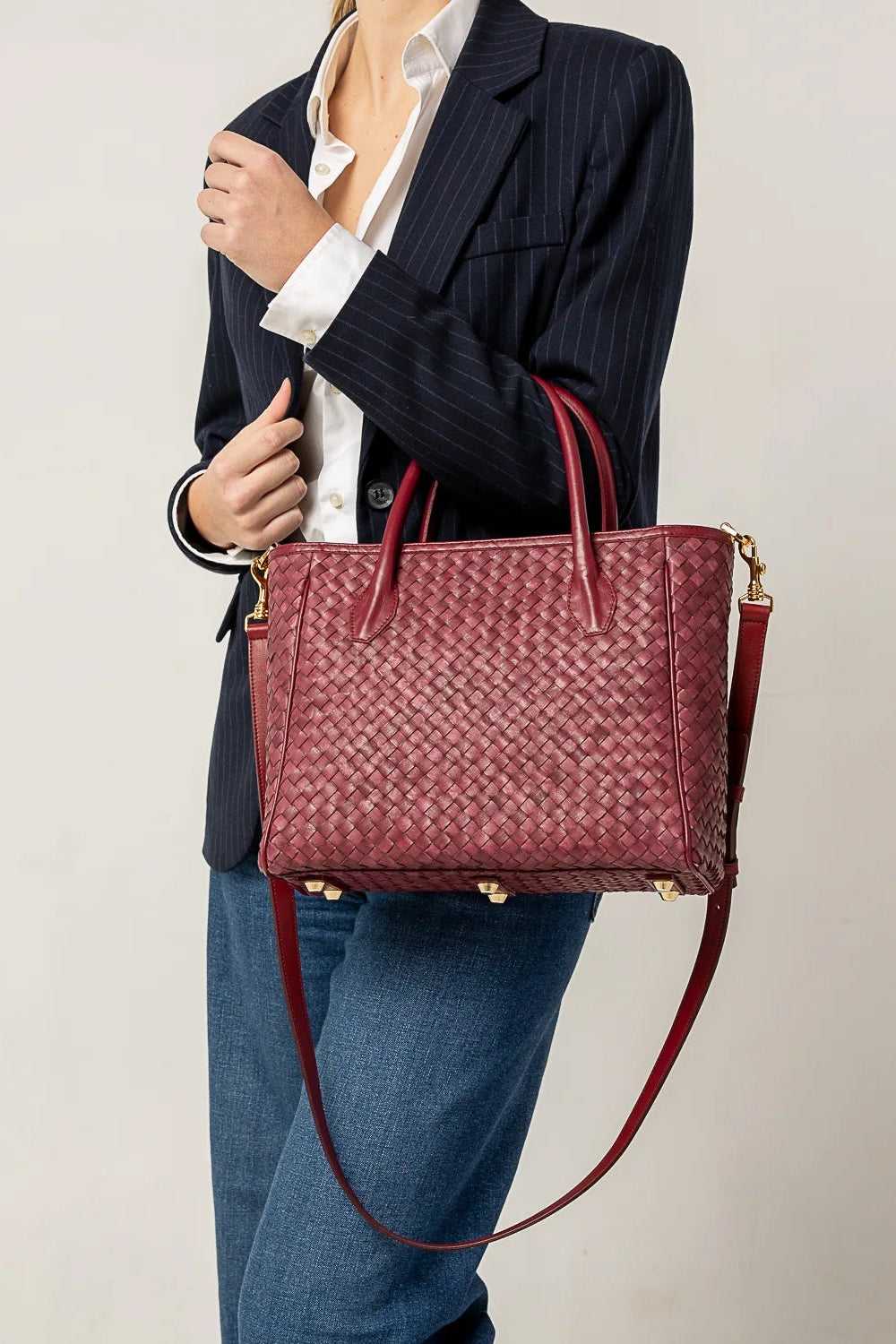 Person holding a red woven handbag against a plain background