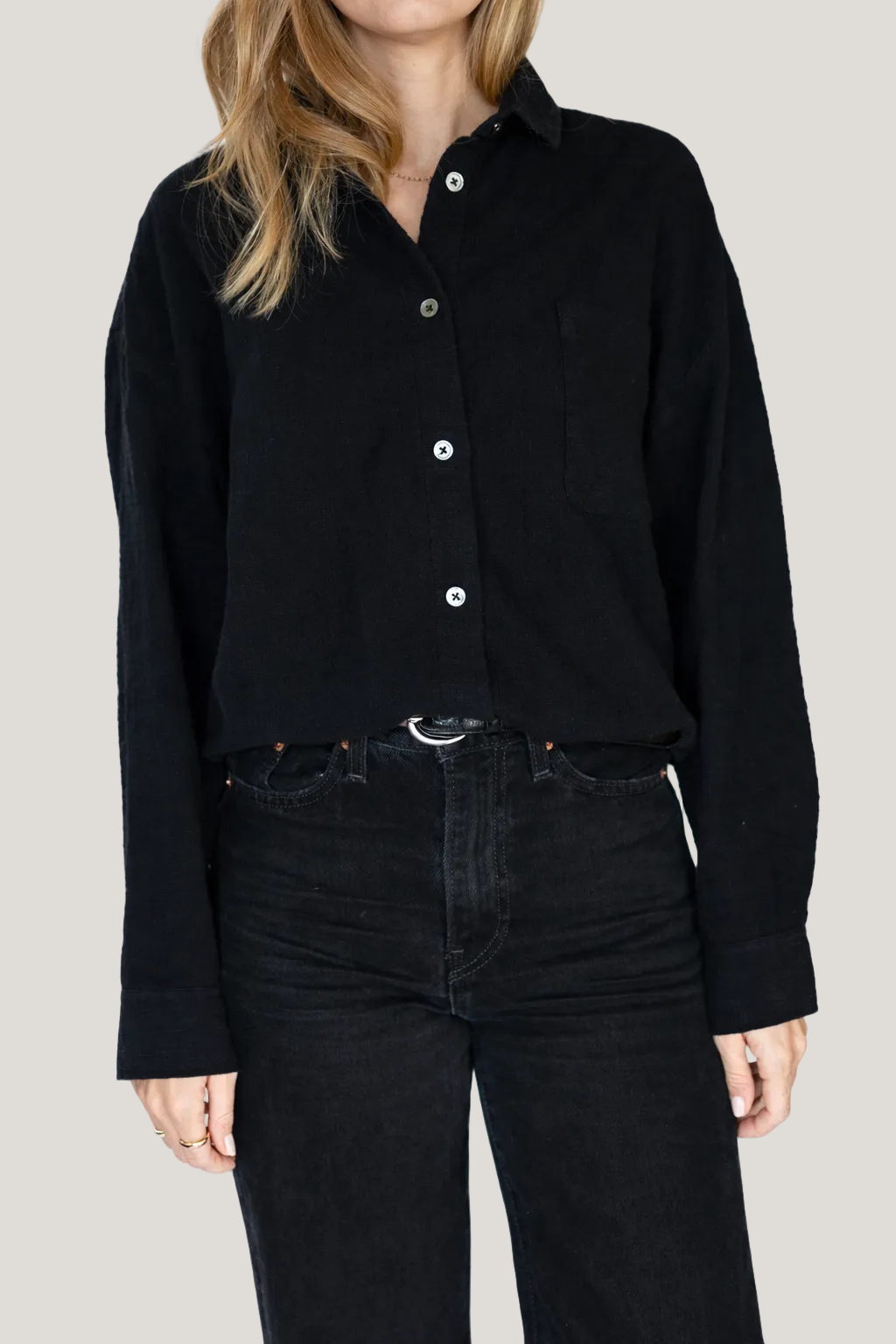 Person wearing a black button-up shirt and black pants on a white background