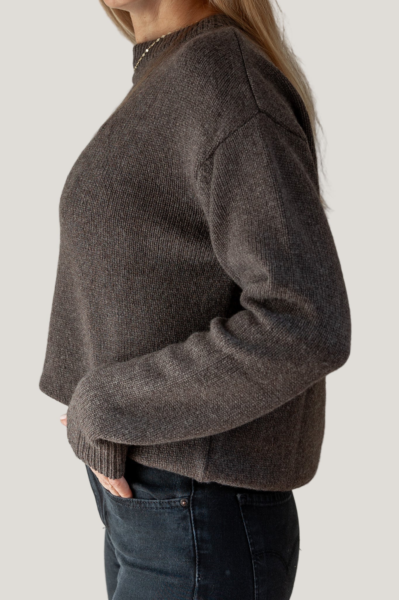 Person wearing a brown sweater against a plain background