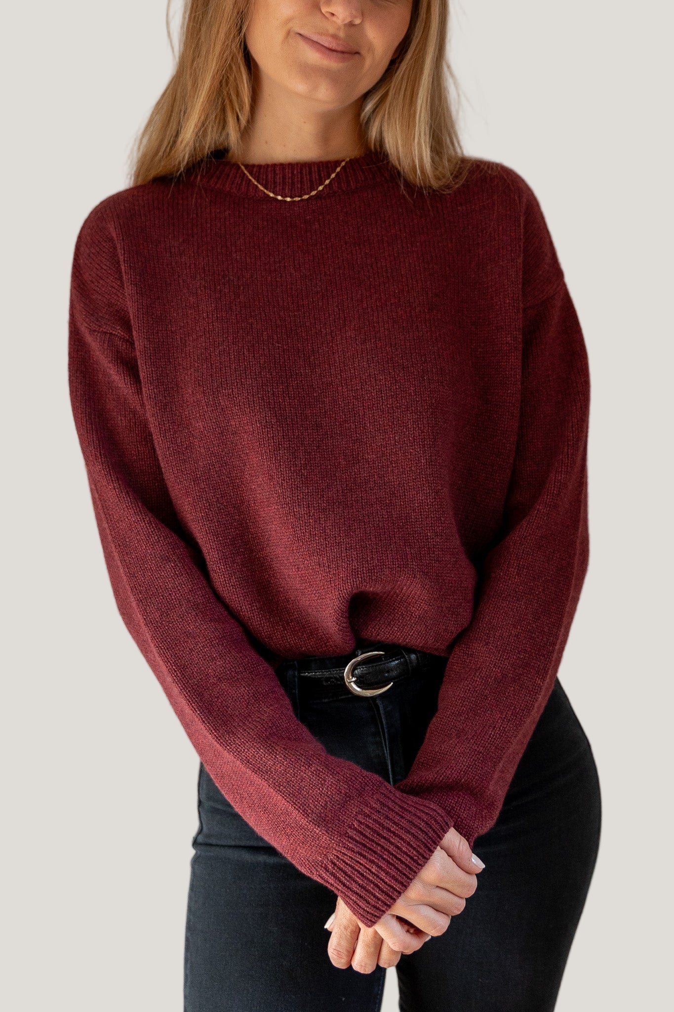 Person wearing a burgundy sweater against a plain background