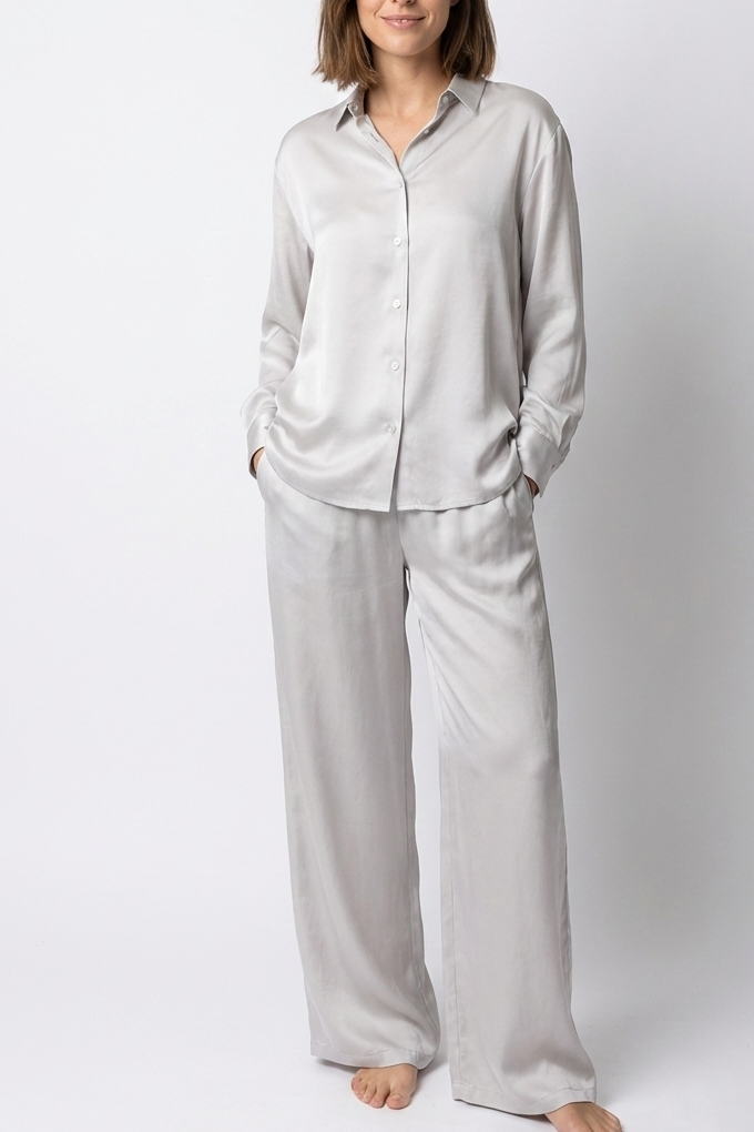 Woman wearing a light gray pajama set against a white background