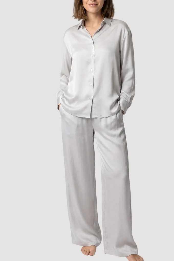 Woman wearing a light gray pajama set against a white background