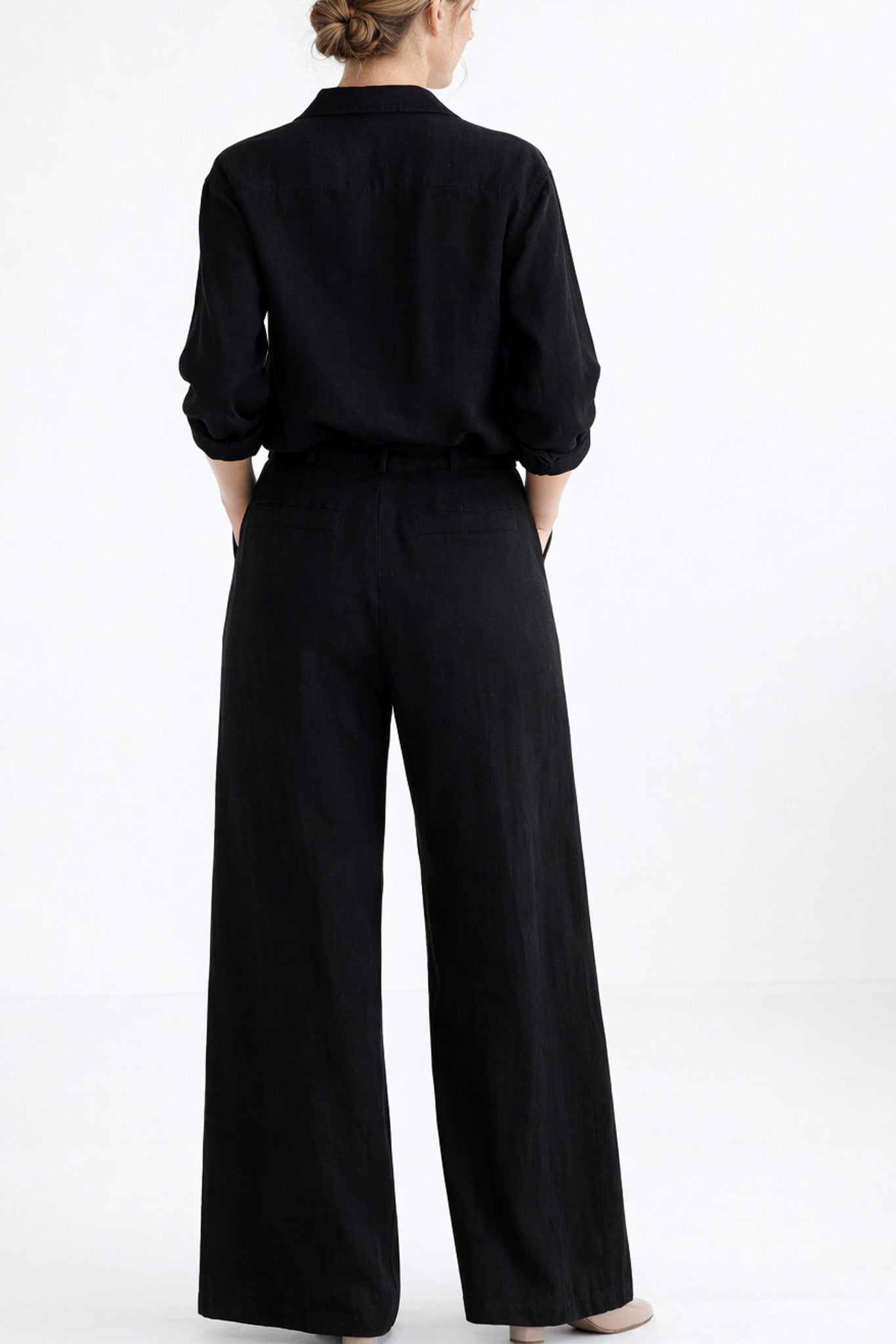 Person wearing a black outfit with wide-leg pants on a white background