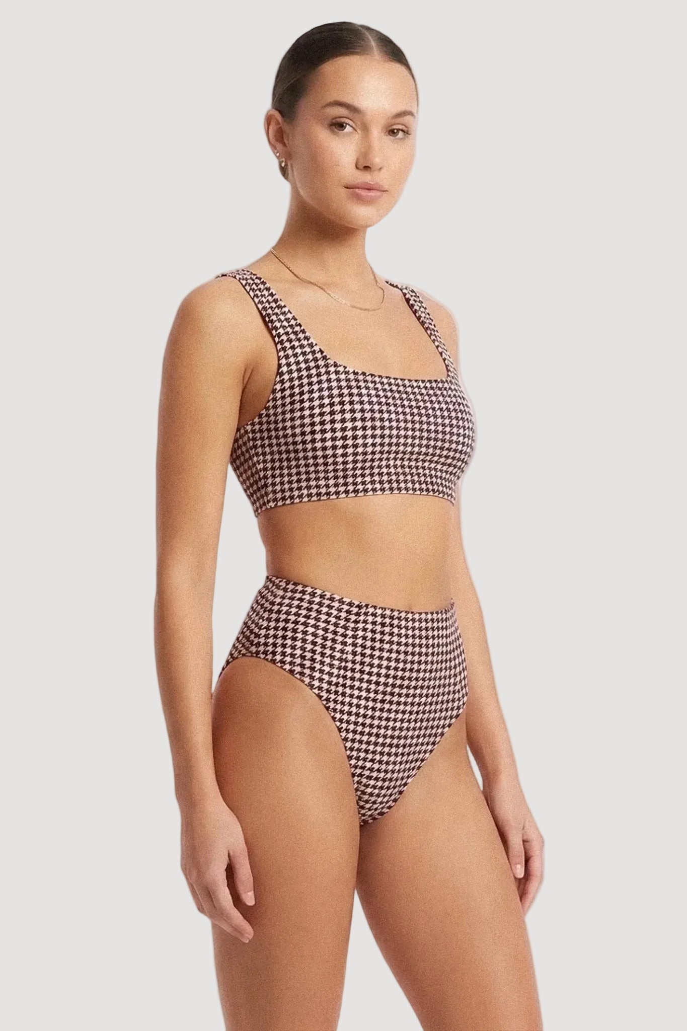 A woman modeling a two-piece bikini set with a BURGUNDY and white houndstooth pattern against a plain white studio background.