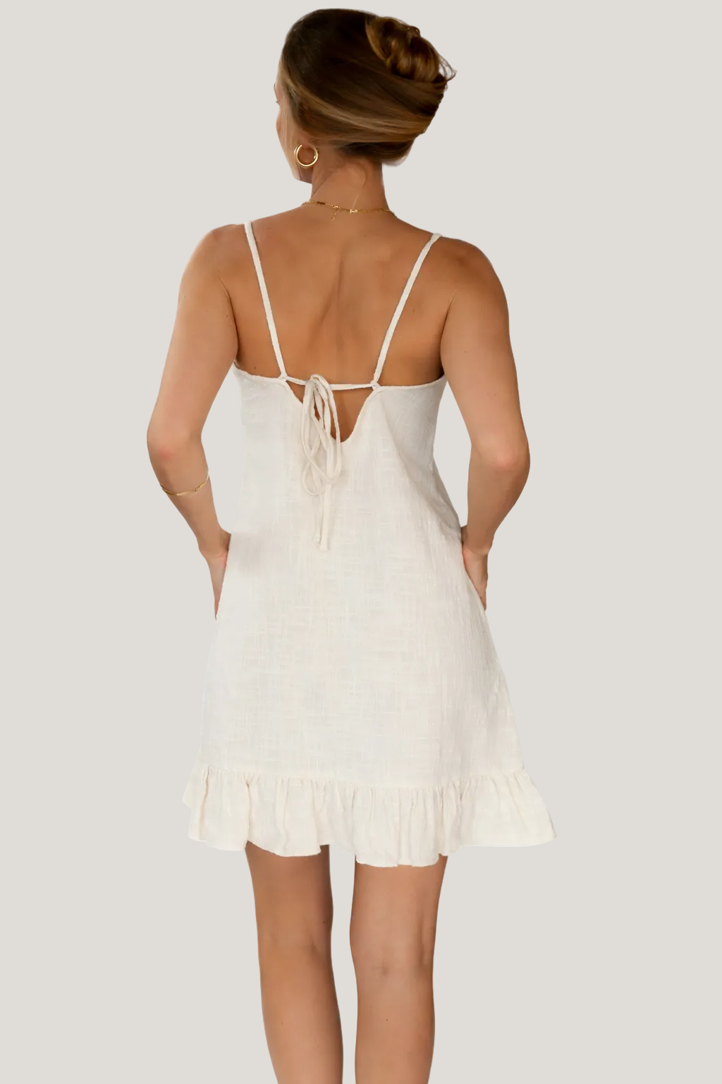 White dress with thin straps and ruffled hem on a white background