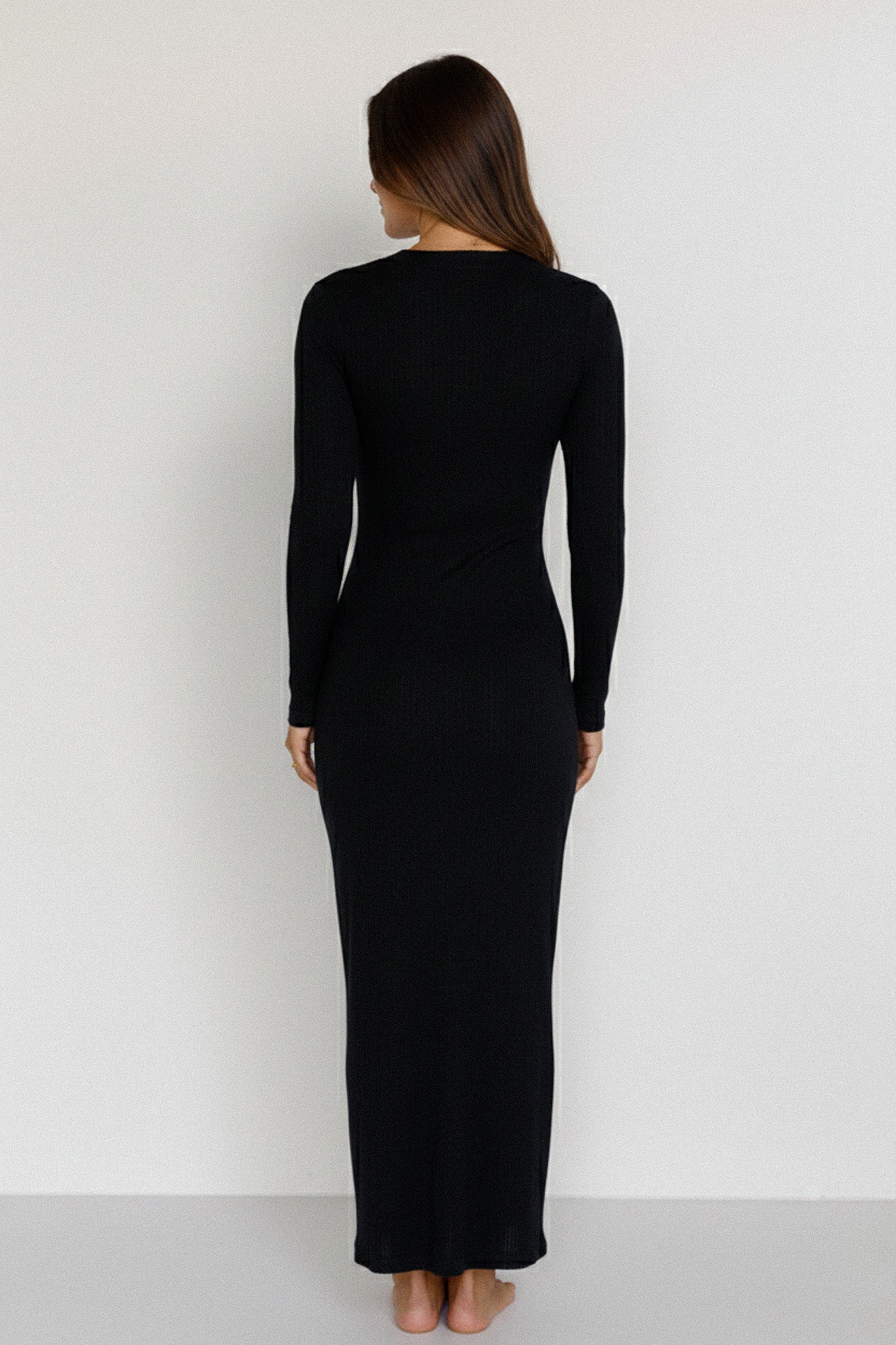 Woman wearing a black long-sleeve dress against a white background