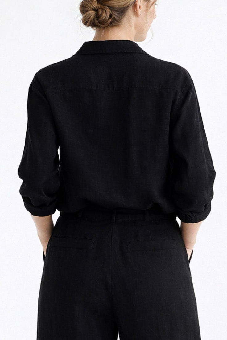 Person wearing a black outfit with wide-leg pants on a white background