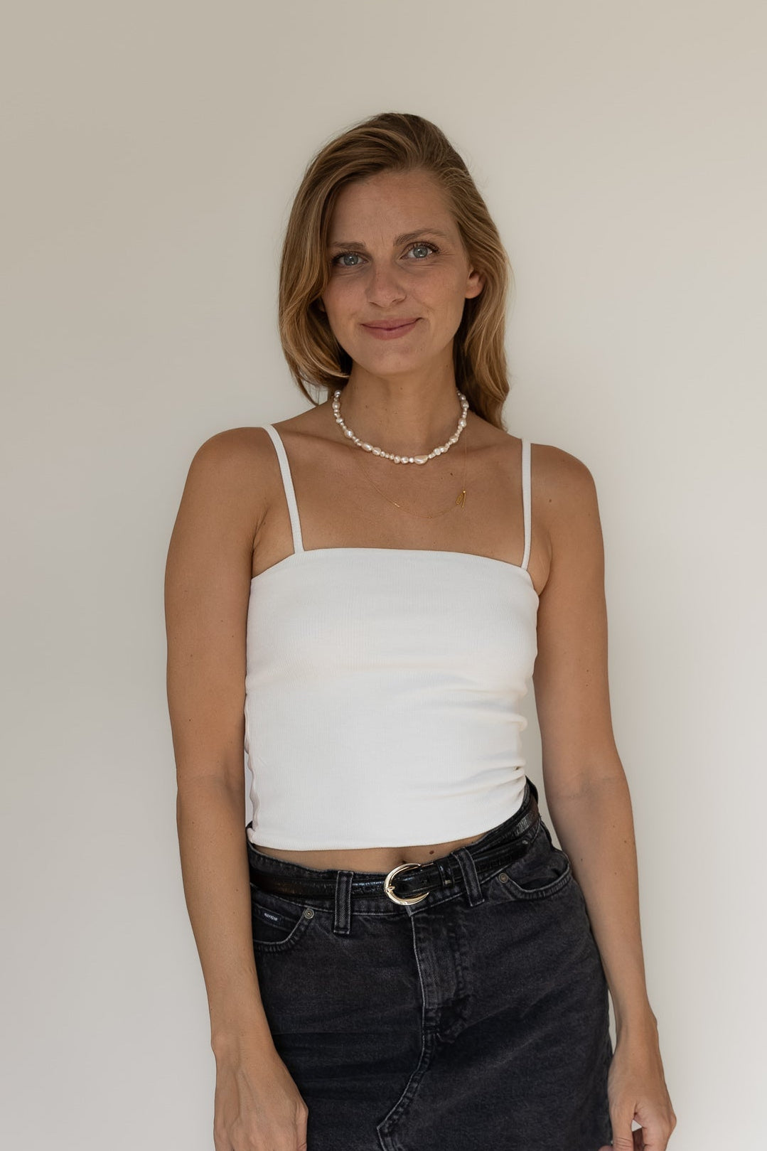 Woman wearing a white top and black skirt against a plain background