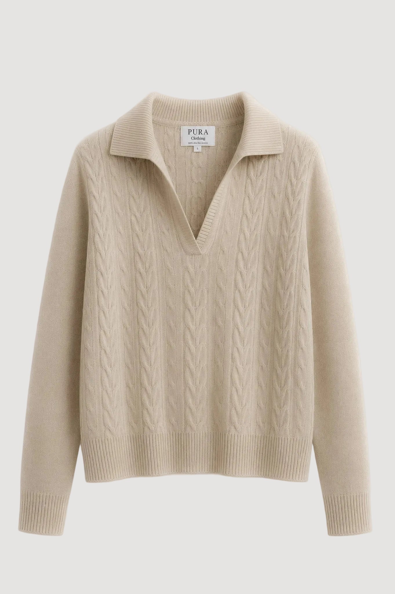 A beige cable-knit sweater with a polo-style collar, shown flat against a clean white background. The brand label 'PURA CLOTHING' is visible inside the collar.