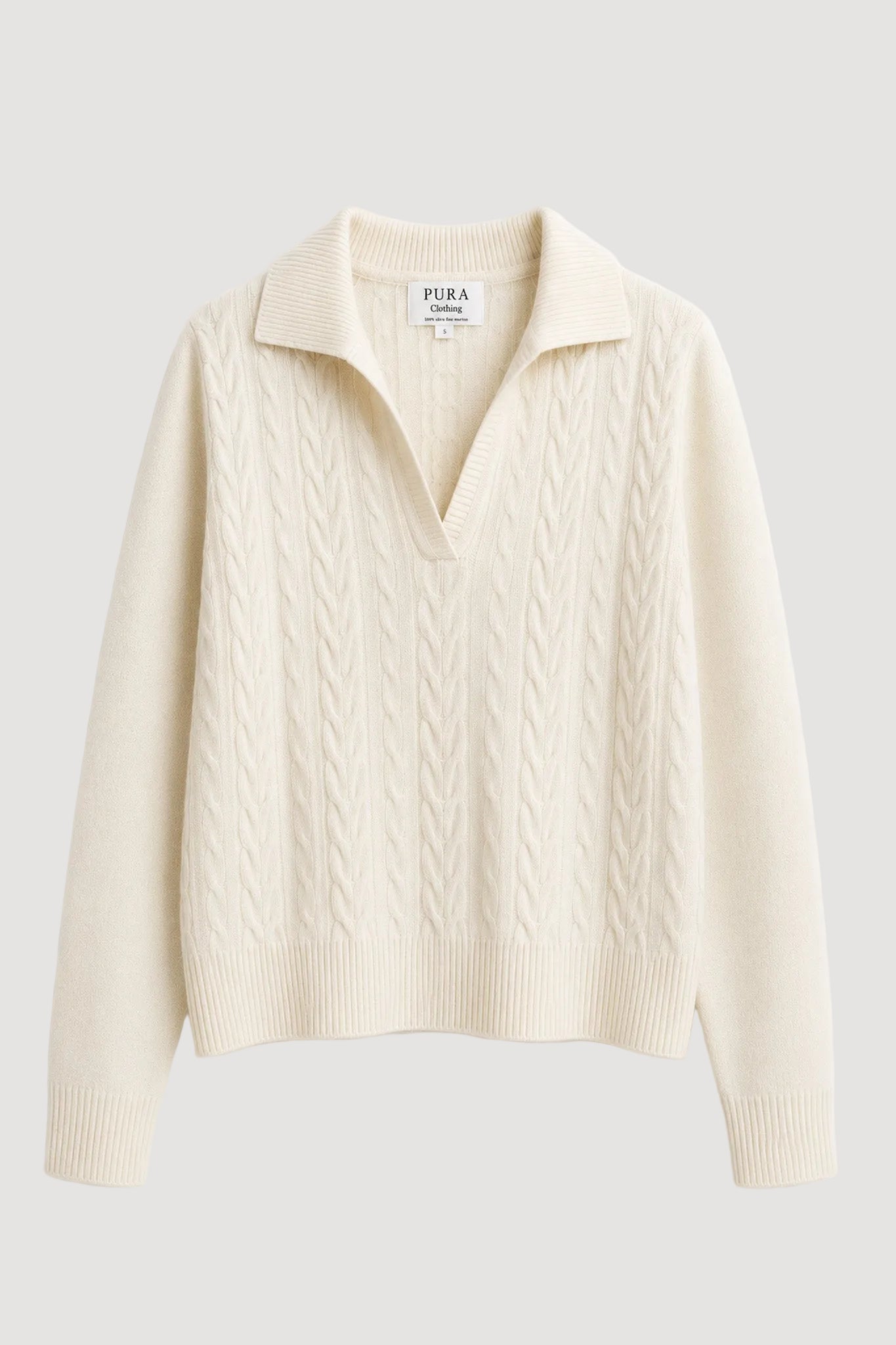 An off-white cable-knit polo sweater with a collar, shown flat against a clean white background. The brand name 'PURA 1914' is visible on the inner neck label.